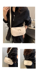Detail of cream PU leather square bag featuring a gold bow buckle and wide strap