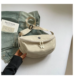 Detail of off-white nylon crescent fanny pack with OK patch and dual zippers