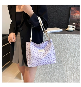 Détail du sac cabas lilas à texture bulles avec motifs nœuds et étiquette logo blanche chic