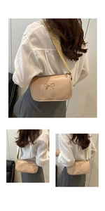 Detail of nude pink shoulder bag with gold bow clasp and wide woven strap on model