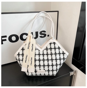 Détail du sac cabas en tweed à carreaux noir et blanc avec des anses élégantes en cuir blanc