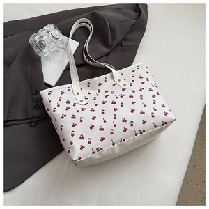 Detail of white cherry print tote bag with lychee texture and gold rivet hardware