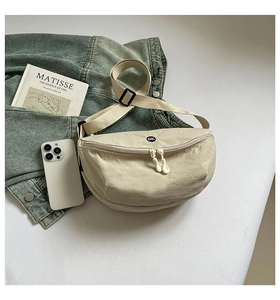 Detail of beige nylon crossbody bag with ok embroidery and adjustable strap