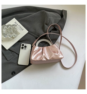 Detailed view of pink ruched cloud bag with pearl handle on grey blazer backdrop