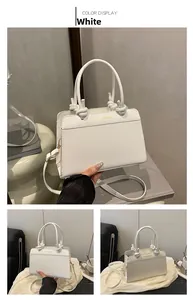 Detail of white box handbag showing knotted handle and gold Fashion Bag logo text