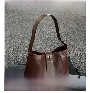 Detail view of smooth coffee oil wax leather underarm bag with gold metal eyelets