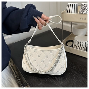 Detailed close-up of cream quilted texture with pearl and silver metal double chains