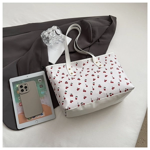 Detailed view of large white leather tote bag featuring vibrant red cherry floral pattern