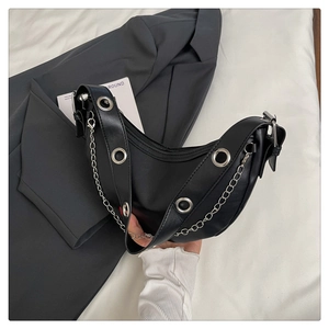 Detail of black leather crescent bag with silver eyelets and chain strap accents