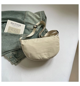 Close-up of beige nylon crescent bag with adjustable strap on minimalist lifestyle background
