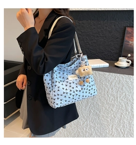 Détail du cabas matelassé bleu clair avec imprimés nœuds et accessoire peluche mignon