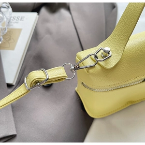 Detail of yellow pebbled leather bag showing silver metal buckle and adjustable strap