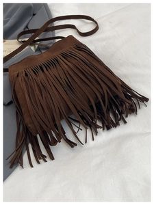 Détail d'un sac seau en daim marron foncé avec de longues franges et une fine bandoulière