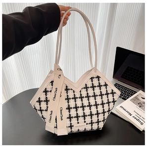 Gros plan d'un sac cabas en tweed à carreaux avec ruban élégant et logo métallique