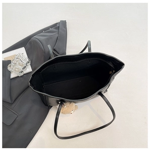 Top view of large black leather tote bag interior with teddy bear charm and inner pocket