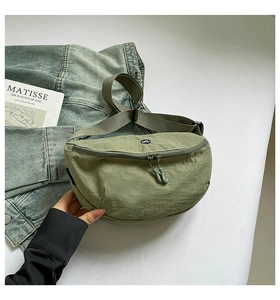 Detail of green nylon crossbody bag showing the dual zippers and OK logo emblem