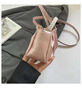 Detailed view of the pink pleated cloud bag featuring a decorative pearl handle and strap