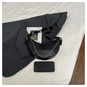 Detail view of black crescent bag with silver chain and metal eyelet strap accents