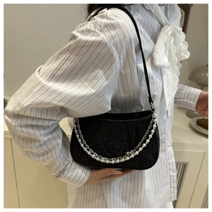 Close-up of black underarm bag with silver chain and white pearl strap detailing