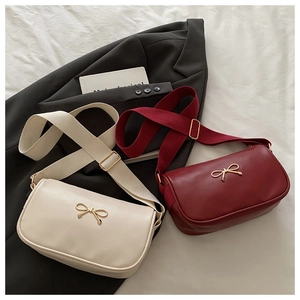 Close-up of minimalist crossbody bags with golden bow buckle and adjustable wide fabric straps