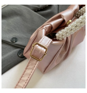Macro view of pleated leather texture and elegant pearl handle on a pink handbag