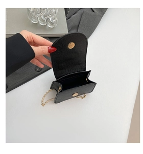 Makroansicht der schwarzen Mini-Tasche mit Litschiprägung und goldenem Kettenriemen