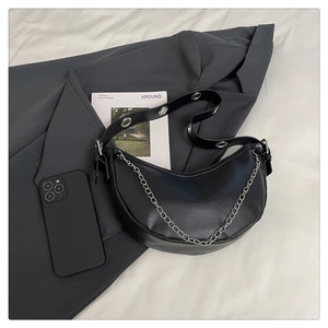 Detail of black faux leather hobo bag with chunky silver chain and wide grommet strap