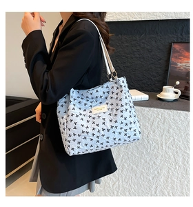 Détail du sac fourre-tout matelassé bleu clair avec imprimé nœuds noirs et étiquette