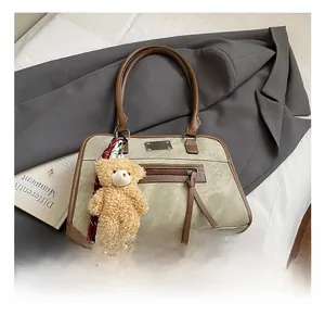 Détail du sac cabas vert olive avec bordures en cuir marron et porte-clé ours en peluche