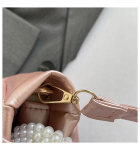Detail of pink pearlescent mini bag with golden metal hook and pearl strap accents