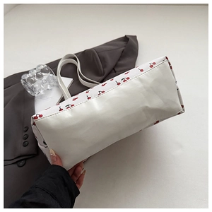 Detail of the high-capacity cherry print tote bag side and smooth white leather base