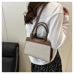 Detail of canvas and brown leather tote bag with FASHION BAG text shown on model
