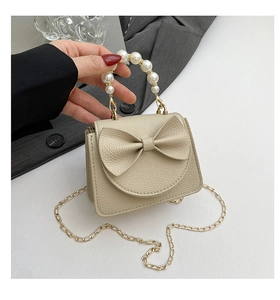 Detailansicht der cremeweißen Minitasche mit Schleife, Perlengriff und goldener Kette