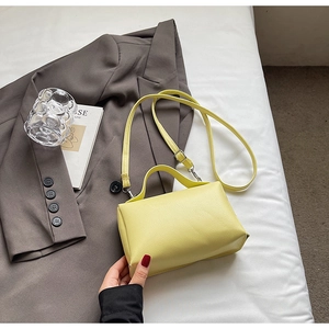 Detail of light yellow textured leather handbag with handle and adjustable strap