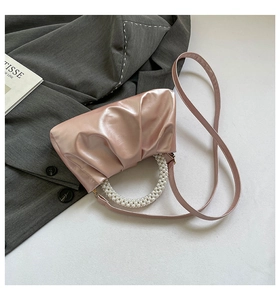 Detail of pink pleated cloud bag featuring pearl handle and adjustable shoulder strap