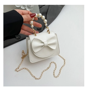 Detail der weißen Mini-Tasche mit großer Schleife, Perlengriff und Goldkette