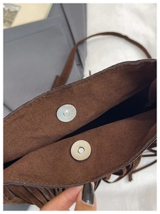Gros plan d'un sac seau en daim marron avec boucles magnétiques et bords à franges