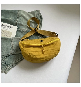 Detail view of a bright yellow nylon crescent chest bag with black OK logo print