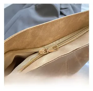 Detail view of smooth light gold metal zipper and textured brown leather on tote bag