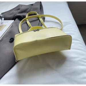 Close-up of a pale yellow lychee leather bag with a cute bow metal zipper puller