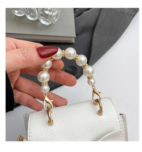 Detail der weißen Mini-Tasche mit Litschimuster und luxuriösem Perlengriff mit Goldakzenten