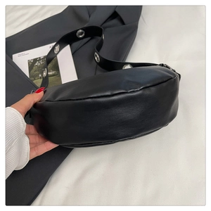 Detail view of black moon bag with textured leather and metal eyelet shoulder strap