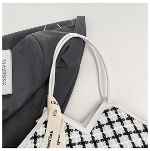 Détail du cabas en tweed noir et blanc avec bordures en cuir et ruban de soie décoratif
