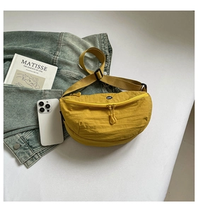 Detail of ginger nylon crescent bag with adjustable strap and circular logo