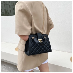 Close-up of black quilted chain bag featuring a gold metal lock and elegant top handle