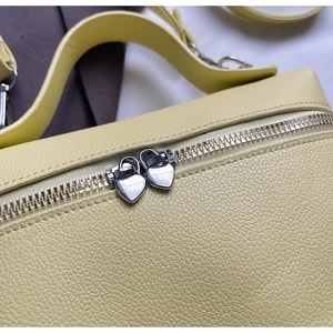 Detail of light yellow lychee grain leather bag with dual heart-shaped silver zippers