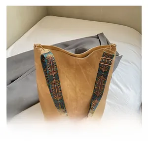 Detail of tan suede tote bag featuring colorful bohemian style wide shoulder strap
