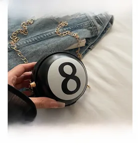 Close-up of creative ball-shaped black 8 billiard bag with gold chain and glossy finish