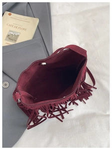 Gros plan du sac seau bordeaux en similicuir suédé avec longues franges et fermoir magnétique