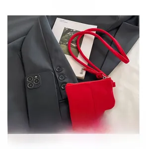 Red suede mini coin bag shown next to a smartphone to demonstrate its compact size
